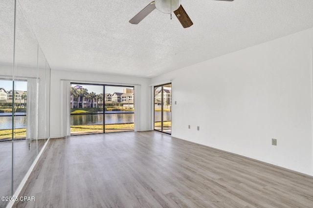 unfurnished room with hardwood / wood-style floors, ceiling fan, and a water view