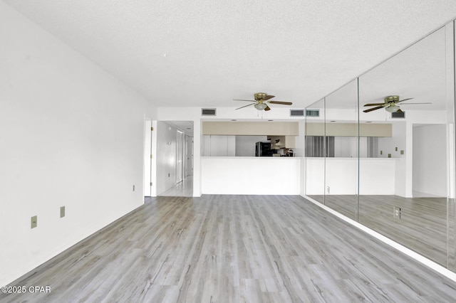 unfurnished living room with a textured ceiling and light hardwood / wood-style flooring