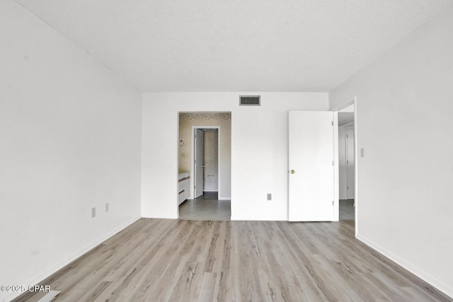 spare room featuring a textured ceiling and light wood-type flooring