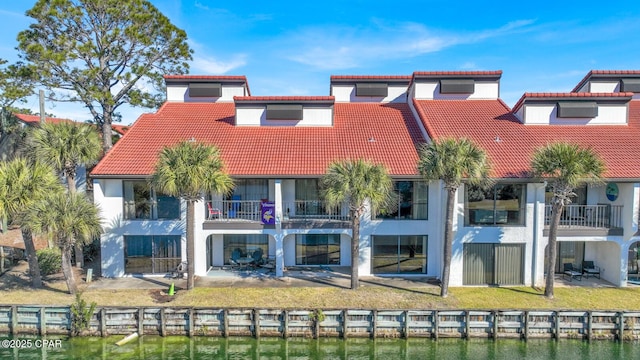 exterior space with a balcony, a lawn, a water view, and a patio area