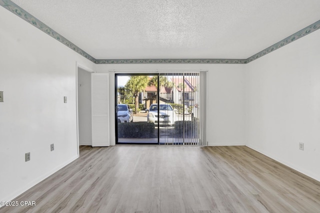 unfurnished room featuring a textured ceiling and light hardwood / wood-style flooring