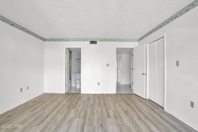 unfurnished room with a textured ceiling and light hardwood / wood-style flooring