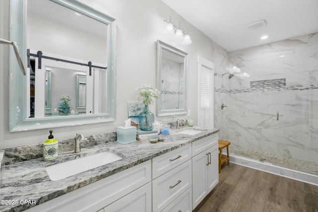 bathroom with a tile shower, vanity, and hardwood / wood-style flooring