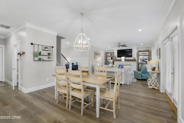 dining area featuring crown molding, wood-type flooring, and ceiling fan with notable chandelier