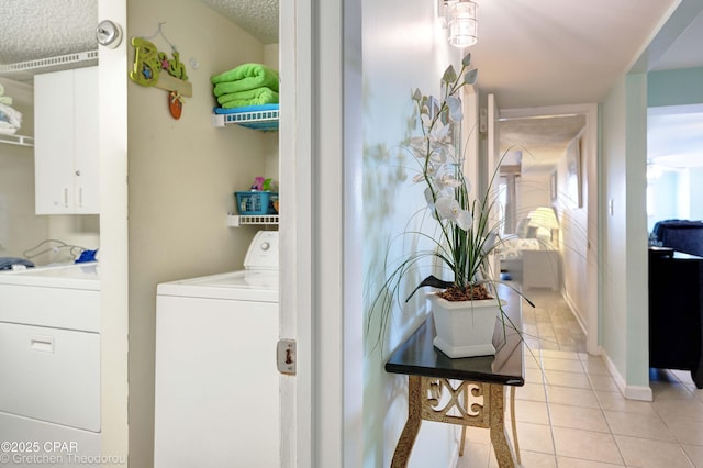 laundry area featuring a textured ceiling, light tile patterned flooring, and washing machine and clothes dryer