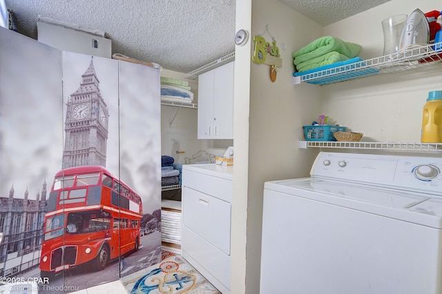 laundry room featuring a textured ceiling, separate washer and dryer, and cabinets