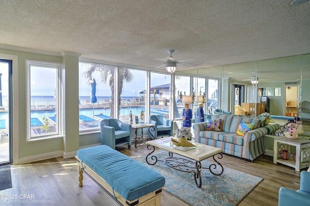 living room featuring a water view, crown molding, ceiling fan, hardwood / wood-style flooring, and a textured ceiling