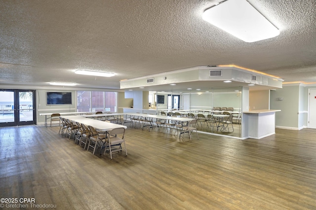 dining space featuring dark wood-type flooring, a textured ceiling, french doors, and plenty of natural light