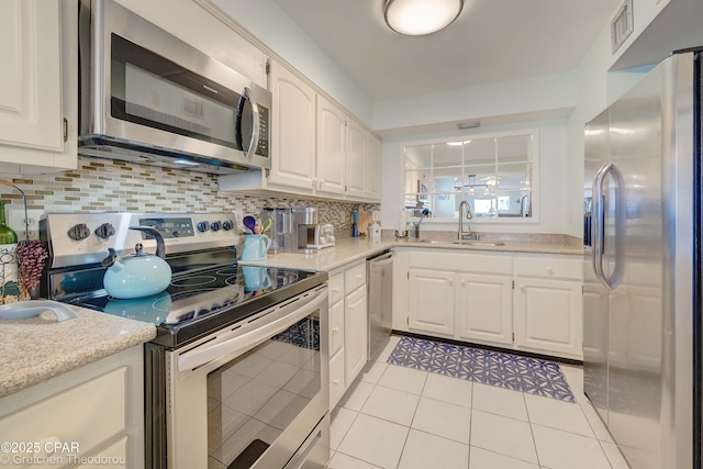 kitchen featuring stainless steel appliances, light tile patterned flooring, white cabinetry, and sink