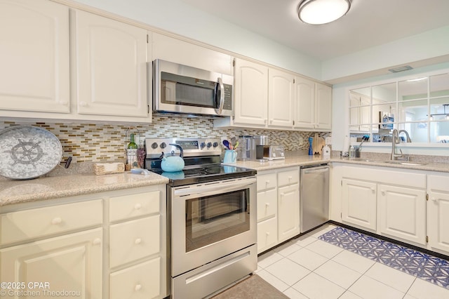 kitchen with appliances with stainless steel finishes, white cabinets, sink, and light tile patterned floors