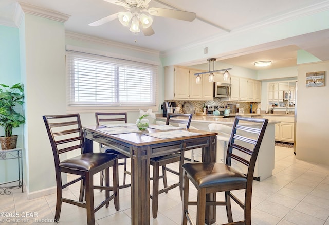 tiled dining space featuring ceiling fan and crown molding