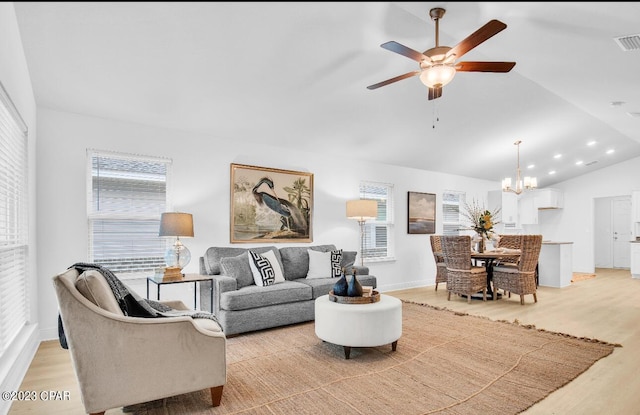 living room featuring ceiling fan with notable chandelier, lofted ceiling, a wealth of natural light, and light hardwood / wood-style floors