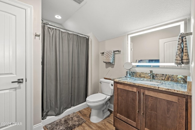 bathroom with hardwood / wood-style floors, lofted ceiling, vanity, toilet, and a textured ceiling