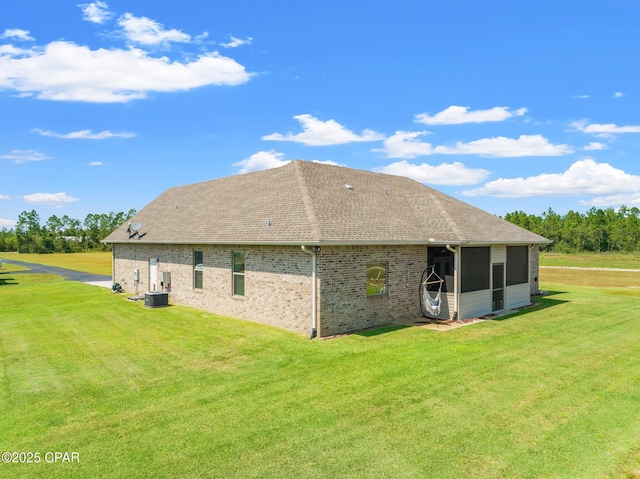 view of property exterior featuring a yard, a sunroom, and central air condition unit