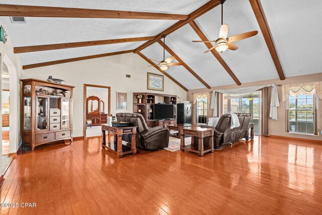 living room featuring ceiling fan, beamed ceiling, high vaulted ceiling, and hardwood / wood-style flooring