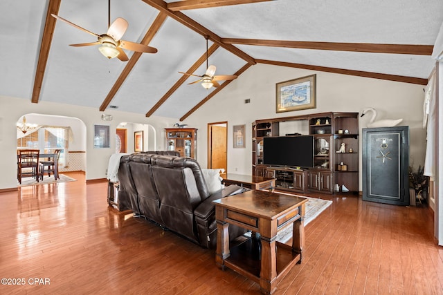 living room featuring beamed ceiling, hardwood / wood-style floors, ceiling fan with notable chandelier, and high vaulted ceiling