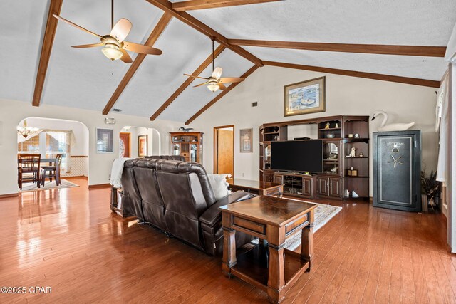 living room with hardwood / wood-style flooring, beam ceiling, ceiling fan with notable chandelier, and high vaulted ceiling