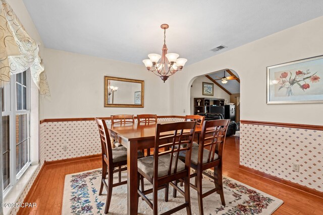 dining area with hardwood / wood-style flooring, lofted ceiling, and ceiling fan with notable chandelier