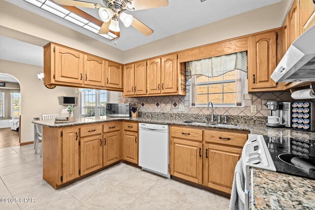 kitchen with stone counters, sink, decorative backsplash, kitchen peninsula, and white appliances