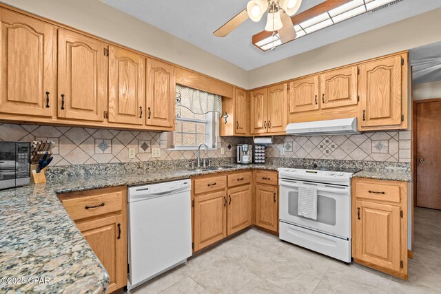 kitchen featuring tasteful backsplash, light stone countertops, sink, and white appliances