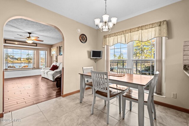 dining area with ceiling fan with notable chandelier, a textured ceiling, and light tile patterned floors