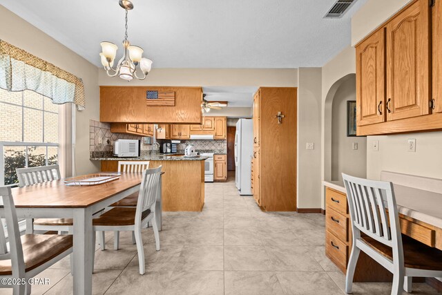 dining area featuring sink, light tile patterned floors, and ceiling fan with notable chandelier