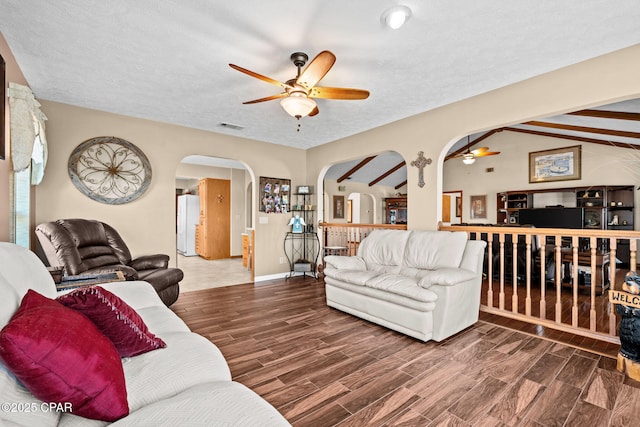 living room with lofted ceiling with beams, a textured ceiling, and ceiling fan