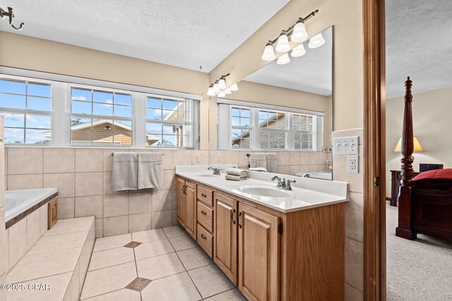 bathroom featuring a healthy amount of sunlight, vanity, a textured ceiling, and tile walls