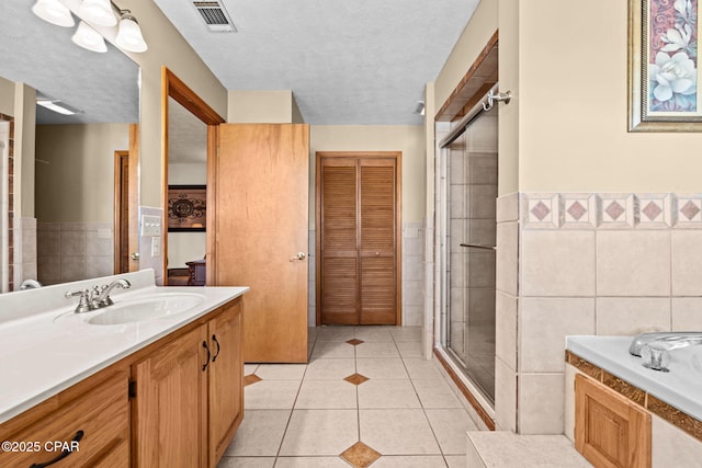 bathroom featuring plus walk in shower, tile walls, tile patterned flooring, vanity, and a textured ceiling