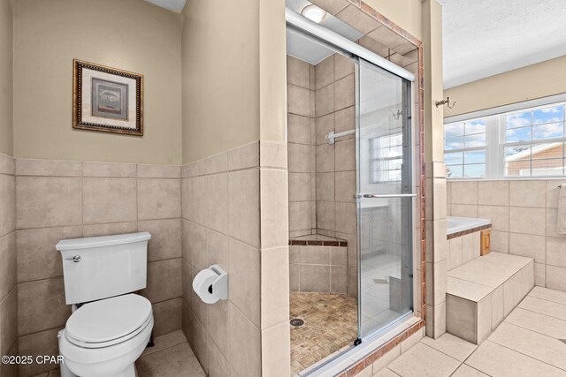 bathroom with tile walls, tile patterned flooring, toilet, and walk in shower