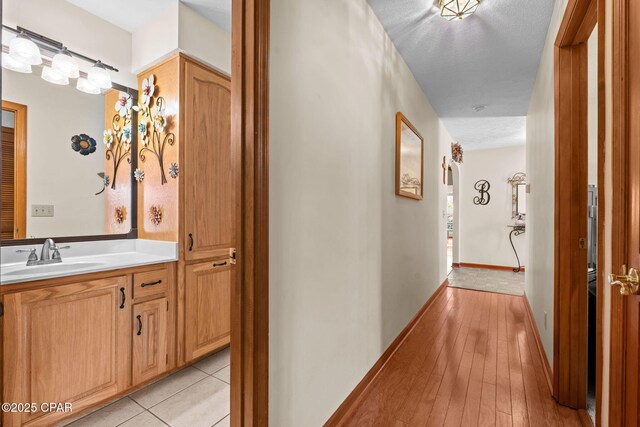 hall featuring sink, light hardwood / wood-style flooring, and a textured ceiling