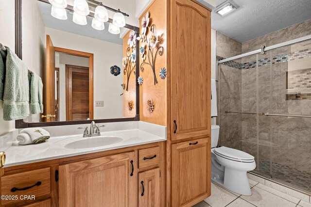 bathroom with vanity, tile patterned floors, toilet, a textured ceiling, and a shower with shower door