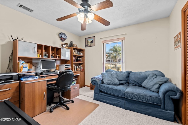 carpeted office featuring ceiling fan and a textured ceiling