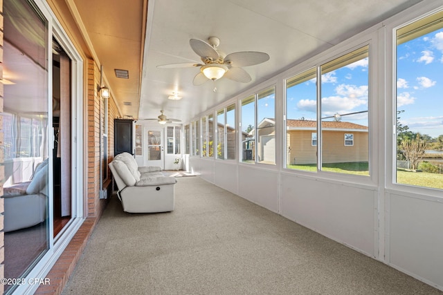 unfurnished sunroom featuring ceiling fan and a healthy amount of sunlight