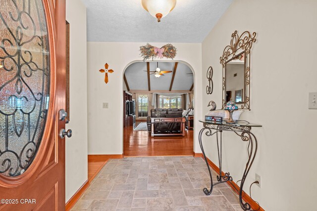 foyer with vaulted ceiling, ceiling fan, and a textured ceiling