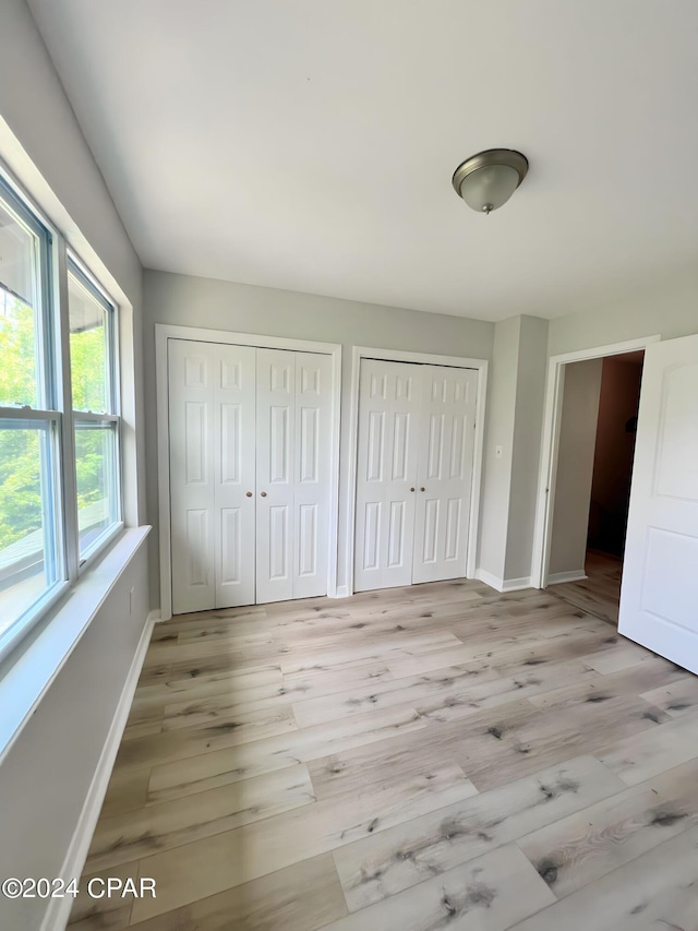 1730 Mallard Dr Apt F, Panama City, FL 32404 - unfurnished bedroom featuring baseboards, multiple closets, and wood finished floors