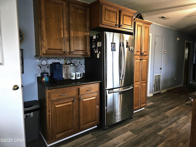 kitchen featuring stainless steel refrigerator, dark hardwood / wood-style flooring, and a textured ceiling