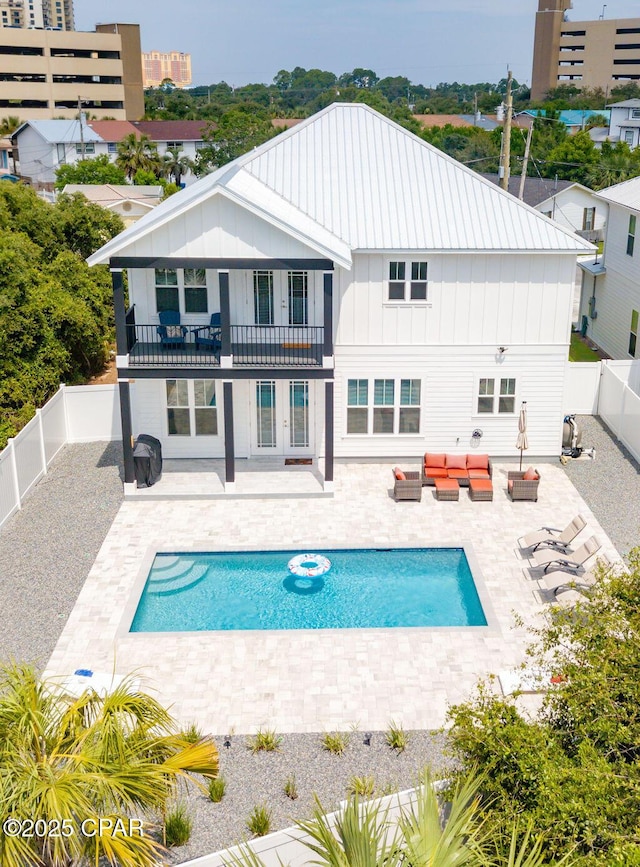 rear view of house featuring a fenced in pool, an outdoor living space, a balcony, and a patio