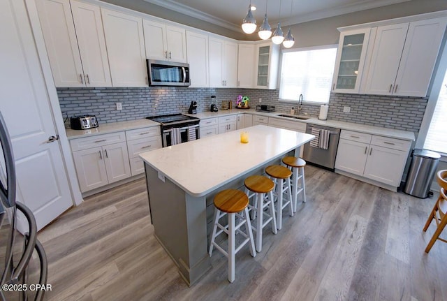 kitchen with white cabinets, appliances with stainless steel finishes, decorative backsplash, and hanging light fixtures