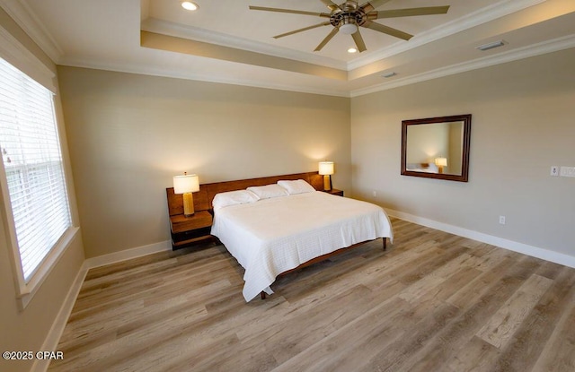 bedroom with ceiling fan, multiple windows, and a tray ceiling