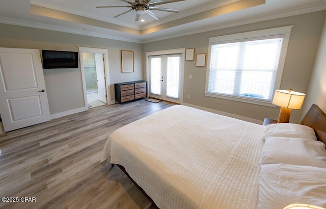 bedroom with a tray ceiling, connected bathroom, ceiling fan, and hardwood / wood-style floors