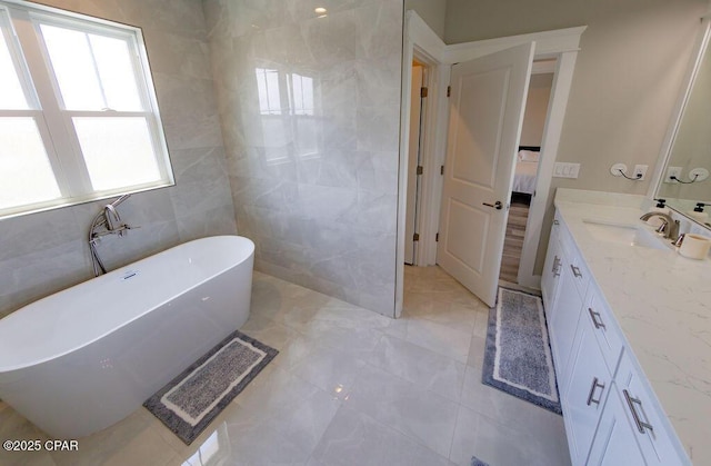 bathroom featuring a washtub, vanity, and tile walls