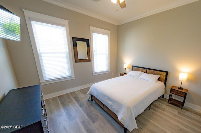 bedroom featuring multiple windows, light wood-type flooring, ceiling fan, and crown molding