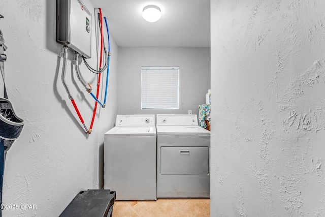 laundry area featuring washer and dryer, laundry area, light tile patterned floors, and a textured wall