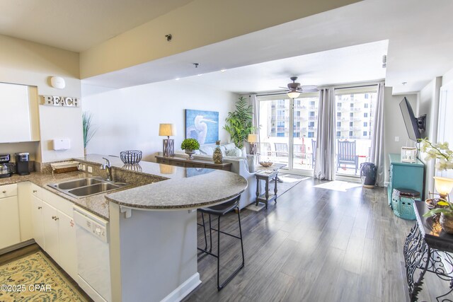 kitchen featuring sink, white cabinets, dishwasher, and a breakfast bar area