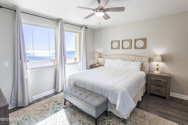 bedroom with ceiling fan, dark wood-type flooring, and a water view