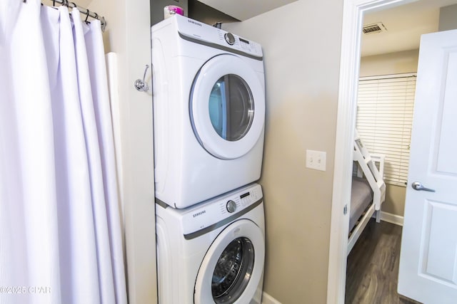 laundry area featuring dark hardwood / wood-style floors and stacked washer and dryer