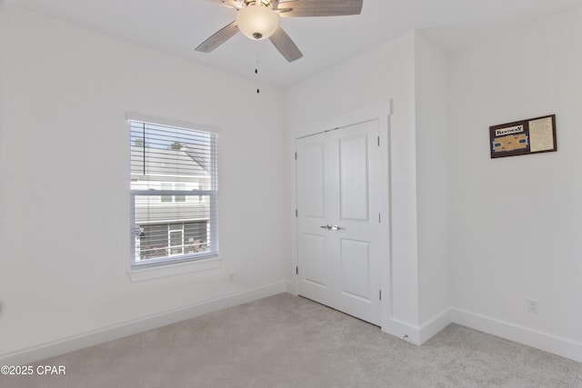 unfurnished bedroom featuring ceiling fan, light carpet, and a closet