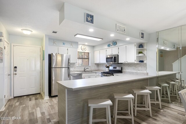 kitchen with sink, a breakfast bar area, white cabinetry, kitchen peninsula, and stainless steel appliances