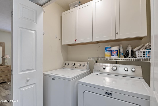 laundry area with wood finished floors, cabinet space, and washing machine and dryer